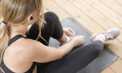Get your workout on woman in workout gear, sits on a yoga mat and ties her shoe
