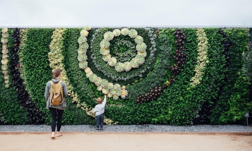 A beautiful community at the heart of all your passions mother and child standing in front of a mural made of plants