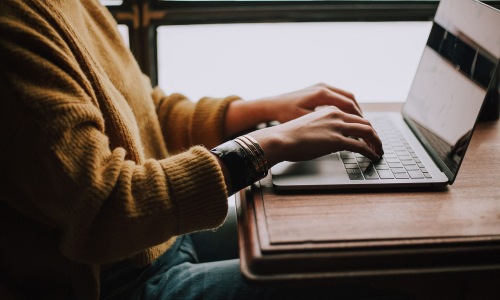 Your new home is waiting woman types on her laptop near large window