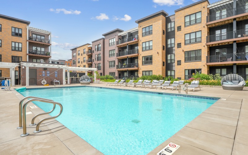 Sparkling outdoor swimming pool with lounge chairs apartments in Brooklyn Park, MN
